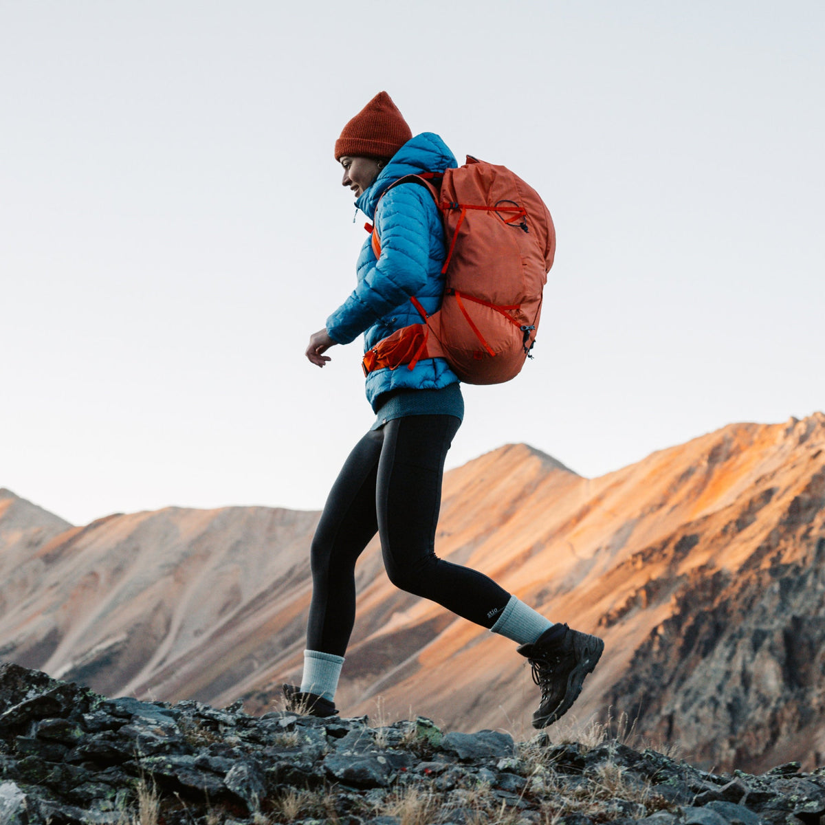 model walking across rocky ground wearing the 5011 micro crew mountaineering sock in reed