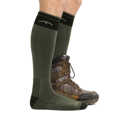 Profile image of a man's legs facing right against a white background wearing Hunter Over the Calf Heavyweight Hunting Socks in Forest with back foot also in a hunting boot