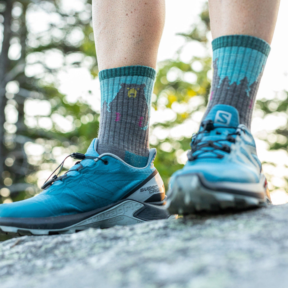 Model standing on a rock in the Women's Bear Town Micr Crew socks